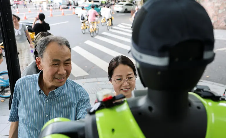 People interact with a humanoid robot traffic police officer developed by SUPCON as it stands on duty on a street in Hangzhou, Zhejiang province, China, July 21, 2026. REUTERS/Go Nakamura