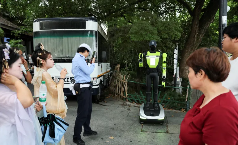 People walk past a humanoid robot traffic police officer developed by SUPCON while it stands on duty on a street in Hangzhou, Zhejiang province, China, July 21, 2026. REUTERS/Go Nakamura