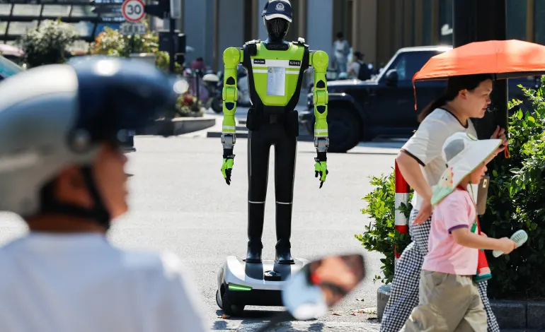 People walk past a humanoid robot traffic police officer developed by SUPCON while it stands on duty on a street in Hangzhou, Zhejiang province, China, July 31, 2026. REUTERS/Go Nakamura
