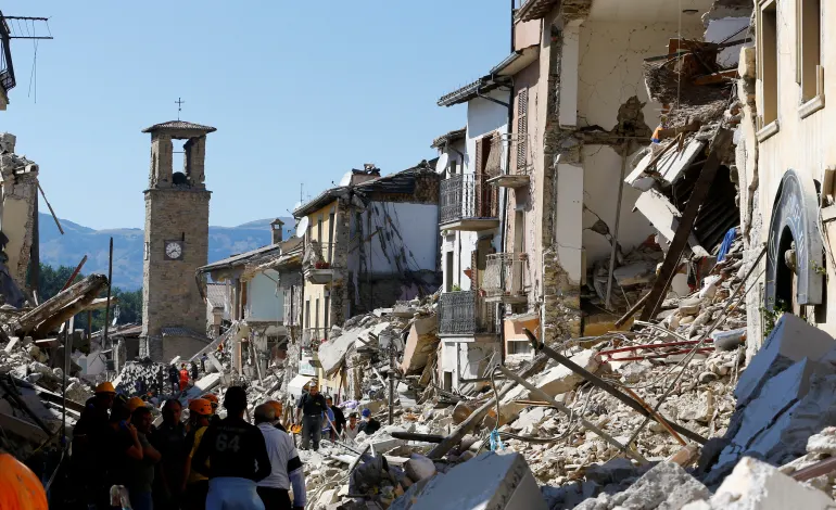 People stand next collapsed buildings following an earthquake in Amatrice, central Italy, August 24, 2016. REUTERS/Stefano Rellandini/File Photo