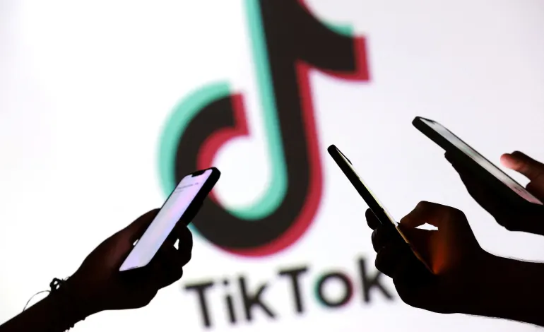 Teenagers pose for a photo while holding smartphones in front of a TikTok logo in this illustration taken September 11, 2025. Dado Ruvic/Illustration