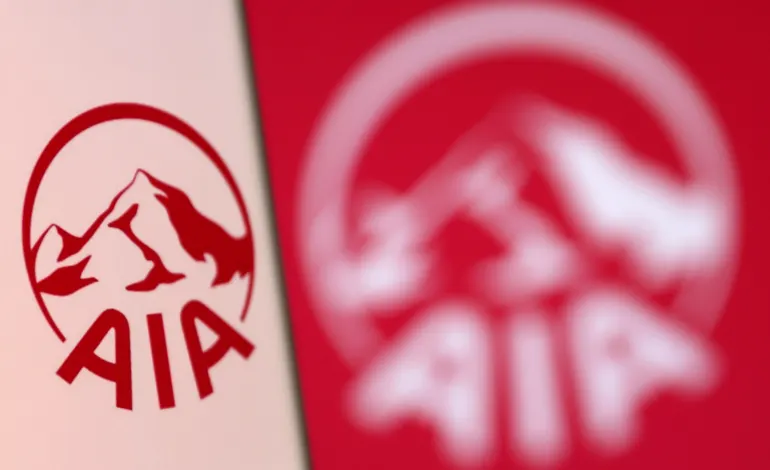 AIA Group logo is pictured on a smartphone in front of an electronic display showing the same logo in this illustration taken, December 4, 2021. Dado Ruvic/Illustration