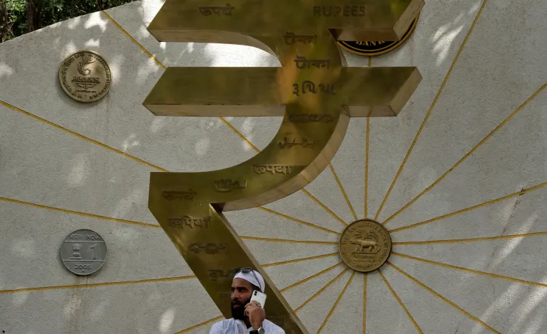 A man speaks on his mobile phone next to an installation of the Rupee logo and Indian currency coins outside the Reserve Bank of India (RBI) headquarters in Mumbai, India, August 1, 2025. Hemanshi Kamani