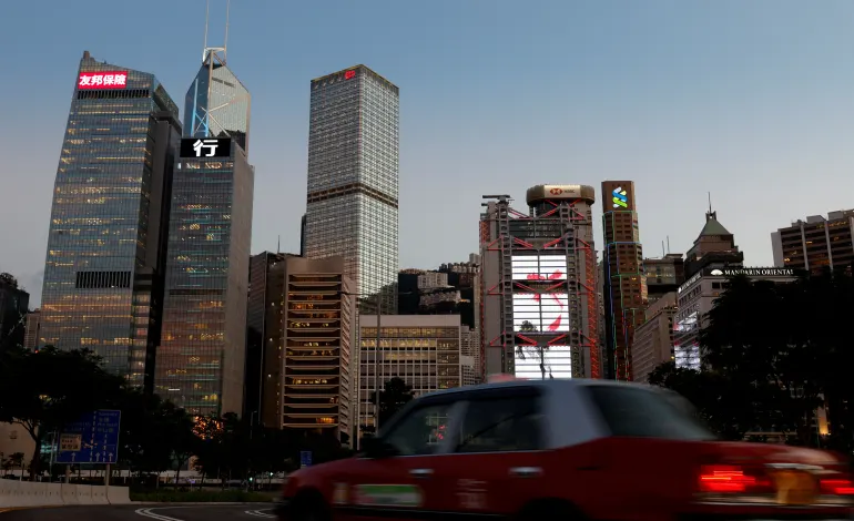 A taxi drives in front of skyscrapers at the central business district, including AIA Central, China Construction Bank (CCB) Tower, Bank of China Tower, Cheung Kong Centre, HSBC and Standard Chartered Bank headquarters, in Hong Kong, China August 17, 2021. Picture taken August 17, 2021. Tyrone Siu