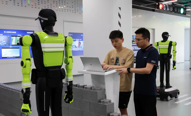 Cao Hui, general manager of SUPCON's Intelligent Unmanned Systems Innovation Center, and an engineer work on a computer as humanoid robot traffic police officers stand at the company's showroom in Hangzhou, Zhejiang province, China, July 21, 2026. REUTERS/Go Nakamura