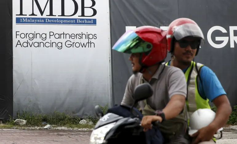 Motorcyclists pass a 1Malaysia Development Berhad (1MDB) billboard at the Tun Razak Exchange development in Kuala Lumpur, Malaysia, February 3, 2016. REUTERS/Olivia Harris/File Photo